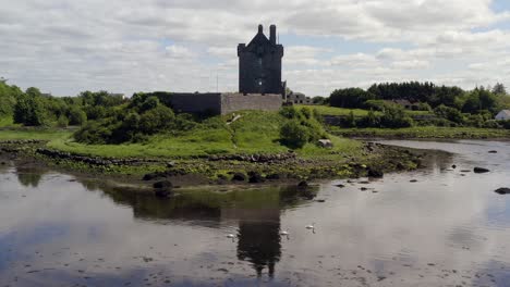 Dolly-Inverso-Del-Castillo-De-Dunguaire,-Kinvara,-Galway,-Con-Reflejos-Simétricos-Y-Cisnes-Deslizándose