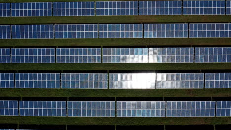 Rows-of-solar-panels-on-a-rooftop,-reflecting-sunlight-from-an-aerial-perspective