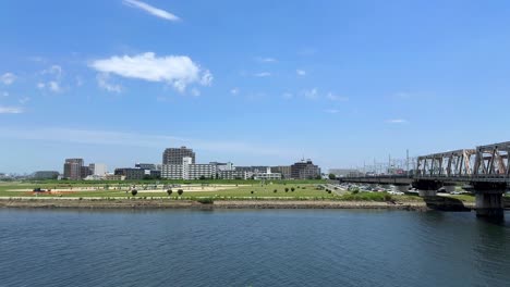 A-scenic-view-of-a-city-skyline-with-buildings-by-a-calm-river-under-a-bright-blue-sky