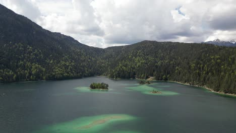 Luftaufnahme-Des-Lebhaften-Eibsees-In-Bayern,-Deutschland,-Umgeben-Von-Natürlichen-Kiefernwäldern-Und-Einer-Entfernten-Bergkette,-Die-Die-Ruhe-Und-Harmonie-Der-Natur-Zeigt