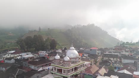 Pequeña-Ciudad-Con-Mezquita-Central-De-Plata-Enclavada-En-El-Místico-Paisaje-Nuboso,-Tierras-Altas-Volcánicas-De-La-Meseta-De-Dieng,-Java,-Indonesia