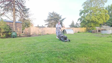 Young-woman-cutting-large-garden-lawn-grass-with-petrol-mower