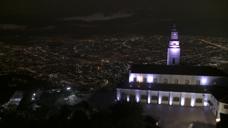 Drone-shot-of-Monserrate-church-overlooking-the-city-of-Bogota,-Colombia-at-night