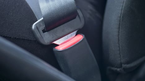 Slow-motion-close-up-shot-of-driver's-hands-pushing-clipping-in-car-seat-belt-clip-into-buckle-vehicle-safety-security-locking-system-into-seat-emergency