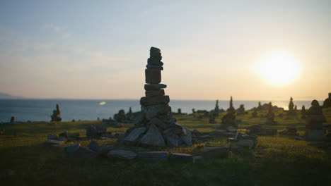 Gestapelte-Steine-Auf-Einem-Feld-Bei-Sonnenuntergang-Am-Meer,-Die-Eine-Heitere-Und-Friedliche-Atmosphäre-Schaffen