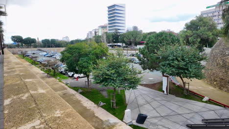 A-scenic-view-of-a-modern-parking-lot-in-Nicosia,-Cyprus,-with-lush-greenery-and-contemporary-buildings-in-the-background,-captured-in-slow-motion