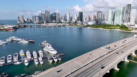 Antena-Sobre-Barcos-Y-Tráfico-Con-El-Horizonte-De-Miami,-Florida,-En-Segundo-Plano.