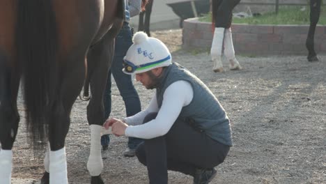 Imágenes-De-Un-Escolta-Vendando-Cuidadosamente-Las-Patas-De-Un-Caballo-De-Carreras-Después-De-Los-Entrenamientos-Matutinos-En-Churchill-Downs,-Preparándose-Para-Las-Próximas-Carreras.