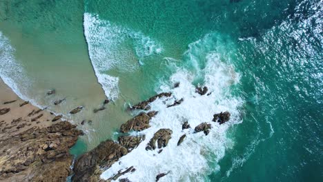 4K-Drone-video-spinning-around-looking-down-on-the-waves-crashing-on-the-rocks-to-reveal-different-landscapes-at-The-Pass,-Byron-Bay-New-South-Wales-Australia