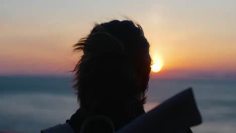 Silhouetted-Woman-Enjoys-a-Beautiful-Sunset,-Rear-View-Slow-Motion