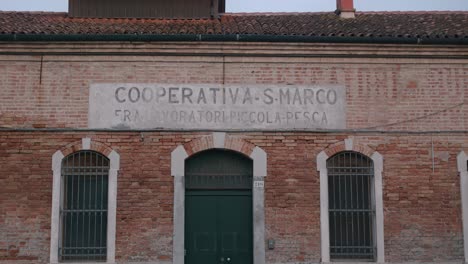 Historic-brick-building-on-Burano-Island,-Venice,-"Cooperativa-S