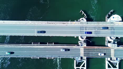 Toma-De-Paisaje-De-Automóviles-Conduciendo-Sobre-La-Carretera-Puente-De-Carretera-Canal-De-Swansea-Lago-Belmont-Macquarie-Entrada-De-Barco-Newcastle-Transporte-Viaje-Drone-Aéreo