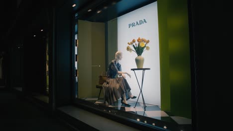 Elegante-Prada-Schaufensterdekoration-Mit-Schaufensterpuppe-Und-Blumenarrangement