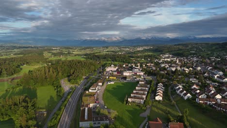 Greifensee,-switzerland,-with-lush-greenery,-houses,-and-mountains-in-the-background,-aerial-view
