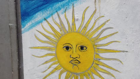 Bandera-Argentina-Pintada-En-Una-Pared-De-Hormigón-Con-Su-Cara-Dorada-Del-Sol-Primer-Plano