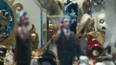 Venetian-masks-and-figurines-displayed-in-a-shop-window,-highlighting-intricate-details