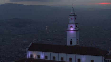 Drohnenaufnahme-Der-Monserrate-Kirche-Mit-Blick-Auf-Die-Stadt-Bogota,-Kolumbien-Zur-Blauen-Stunde