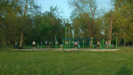 People-exercising-in-an-outdoor-gym-surrounded-by-greenery-at-Jarun-Lake,-Zagreb-Croatia