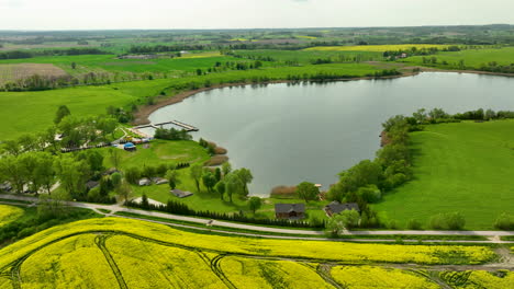 Luftaufnahme-Eines-Kleinen-Dorfes-Am-Seeufer-Mit-Häusern-Und-Viel-Grün-Rund-Um-Das-Wasser