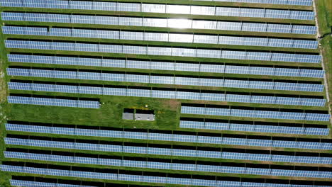 Eine-Große-Solarpanel-Farm-Auf-Einer-Grünen-Wiese-An-Einem-Sonnigen-Tag,-Luftaufnahme