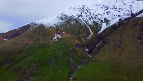 Luftaufnahme-Einer-Riesigen-Wildnis-Mit-Schneebedeckten-Gipfeln,-Zerklüftetem-Gelände-Und-Dramatischen-Wolkenlandschaften