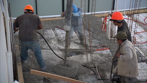 Slow-motion-of-a-group-of-mexican-latin-construction-workers-pouring-fresh-concrete-with-a-boom-pump-to-create-the-slab-of-a-house-in-Mexico