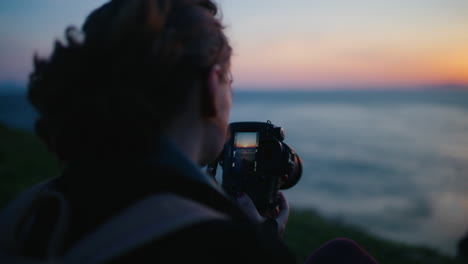 Mujer-Fotografiando-Puesta-De-Sol-Sobre-El-Mar-Y-Mira-La-Cámara-En-Cámara-Lenta