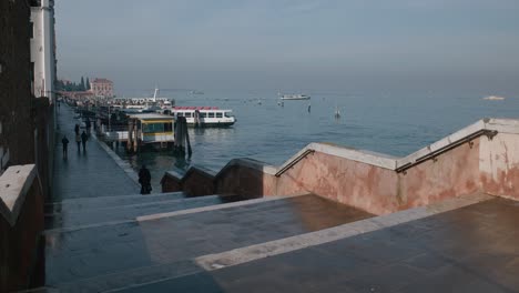 Malerische-Aussicht-Auf-Eine-Uferpromenade-Mit-Booten,-Die-Entlang-Des-Kanals-In-Venedig,-Italien-Angedockt-Sind