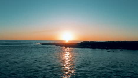 Aerial-shot-with-drone-upward-movement-of-sunset-and-dusk-in-mouth-that-connects-the-Pacific-Ocean-and-estuary-island-in-the-foreground