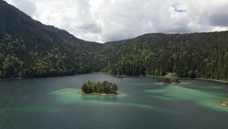 Aerial-view-of-the-vibrant-Eibsee-Lake-in-Bayern,-Germany,-with-small-islands-dotting-the-water-and-surrounded-by-mountainous-forests,-highlighting-the-concept-of-natural-beauty-and-serenity
