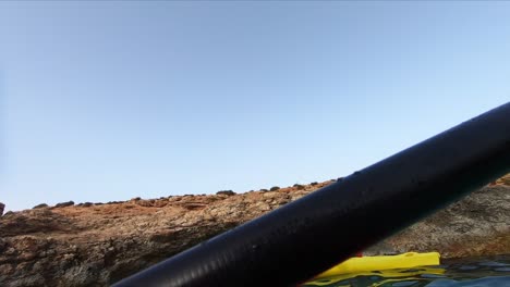 Kayaking-through-a-low-rocky-natural-window-like-formation-in-the-Mediterranean-Sea-at-Comino-island,-Malta