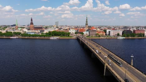 Un-Dron-Delantero-Disparó-Sobre-Un-Puente-De-Piedra-En-Riga,-Letonia,-Mientras-El-Tranvía-Viaja-Por-El-Centro.