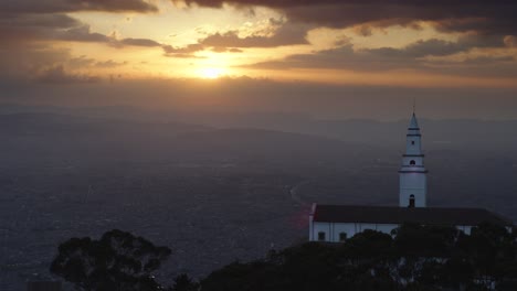 Drone-shot-of-Monserrate-church-overlooking-the-city-of-Bogota,-Colombia-at-sunset