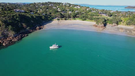 Yacht-In-Oneroa-Bay-Floating-Near-The-Sandy-Beach-With-Jade-Rock-In-Waiheke-Island,-Auckland,-New-Zealand