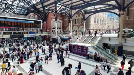 Busy-day-at-London-Liverpool-Street-Station-with-people-walking,-waiting,-and-checking-the-train-schedule-on-the-concourse