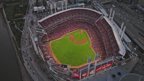 Cincinnati-Ohio-Aerial-v22-birds-eye-view-flyover-Great-American-Ball-Park,-cheering-fans-on-bleachers-as-Reds-play,-tilt-up-reveals-downtown-sunset-cityscape---Shot-with-Inspire-3-8k---September-2023