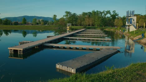 Modern-docks-extending-into-a-calm-lake-with-reflections-and-distant-mountains-in-Jarun-Lake,-Zagreb-Croatia