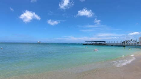 Slow-Motion-View-Of-Gentle-Waves-Breaking-On-Beach-Beside-Pier-In-Waikiki,-Hawaii