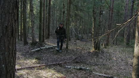 Forest-hunter-walking-in-a-forest-with-a-rifle-looking-for-a-prey