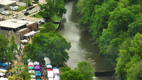 The-dogwood-fest-in-arkansas-showing-a-river-surrounded-by-lush-greenery,-aerial-view