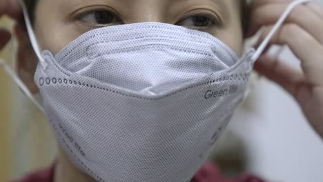 Asian-Lady-wearing-a-mask-to-protect-herself-from-coronavirus,-front-view,-close-up,-slow-mo-footage