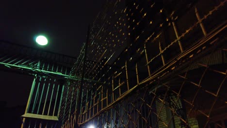 Dark-abandoned-prison-yard,-sharp-fences-visible-at-night,-the-outside-lamp-is-shining