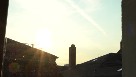 Time-Lapse-View-Through-Window-Of-Yellow-Golden-Sunset-Over-Buildings-In-Frankfurt,-Germany