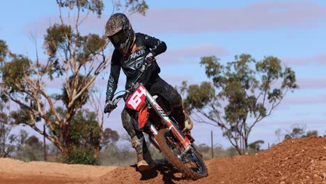 Motocross-bike-racing-over-a-rise-in-the-dirt