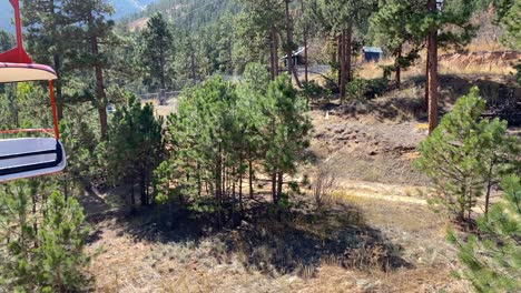 Chair-of-aerial-tram,-Colorado-amusement-park-ride-in-pine-tree-forest-scenery