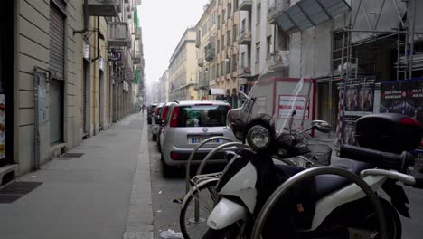 Cityscape-with-vehicles-parked,-vespa-at-foreground.-Handheld