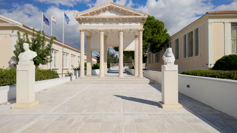 A-neoclassical-building-in-Pafos,-Cyprus,-with-columns-and-busts,-under-a-bright-blue-sky
