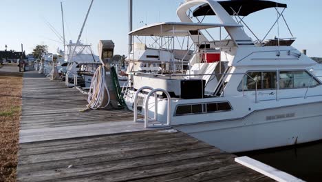 Wide-shot-of-Sag-Harbor-marina-boardwalk-with-anchored-boats-on-a-fall-evening