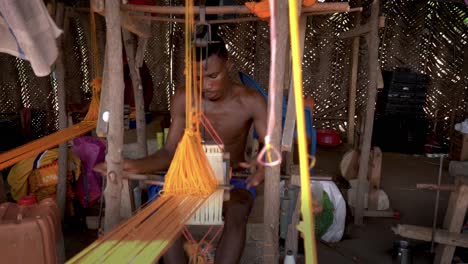 Un-Tejedor-Experto-Trabaja-Rápidamente-En-Un-Telar-De-Madera-En-Ghana,-África-Occidental,-Tejiendo-La-Colorida-Tela-Kente-Para-La-Ropa-Tradicional-Africana.