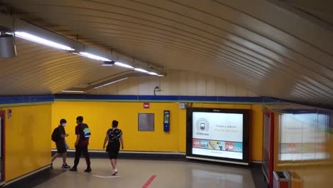 Descending-on-escalator-in-Madrid-metro-behind-commuters,-slow-motion